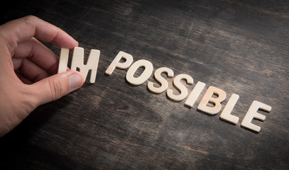 hand taking of the wooden letters in from the word impossible so it says possible.