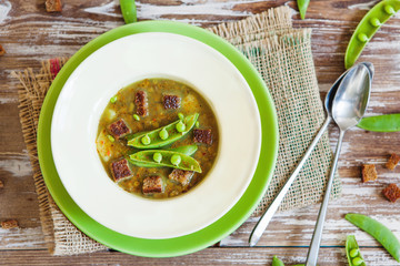 Bean soup in bowl with fresh green pea pods and rye toasts