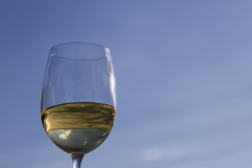 A glass of white wine against the blue sky