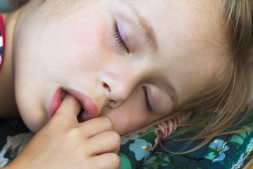 Little pretty girl sleeping, sucking thumb and having sweet dreams