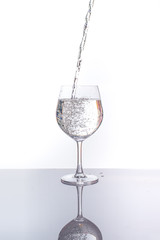 pouring water into a glass wine on white background