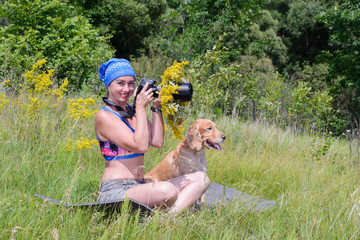 Girl photographer with dog cocker spaniel in a meadow among flowers and grass