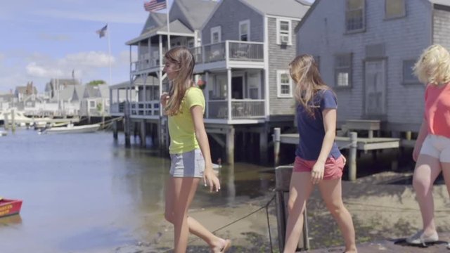 Girls Walk Single File Along Sea Wall On Nantucket Island (Slow Motion)