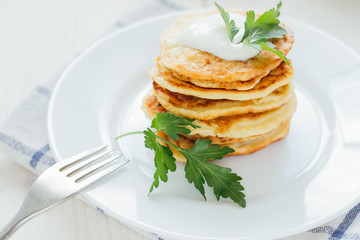 Stack of fried vegetable fritters with sour cream on top 