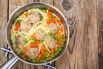 Vermicelli soup with meatballs on wooden background