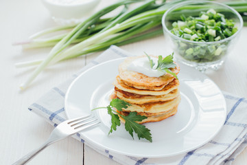 Stack of fried vegetable fritters with sour cream on top 