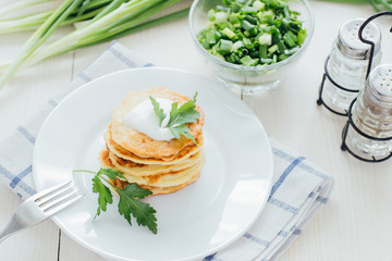 Stack of fried vegetable fritters with sour cream on top 