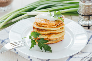 Stack of fried vegetable fritters with sour cream on top 