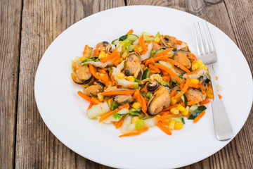 Peking cabbage, corn, cucumber, mussels on a white saucer on an 