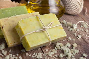 Collection of handmade, natural organic soap and cosmetic oil on wooden background. Spa products. Purple tinted