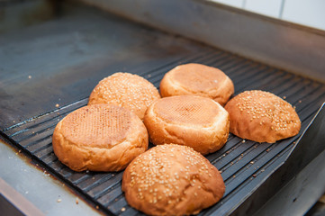 Burger restaurant menu cooking process. Buns are fried on a grill. Fast food cafe cuisine. Selective focus. close up