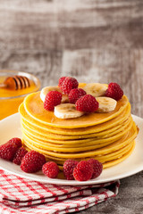 Fresh made delicious pancakes with berries, blackberries, raspberries, banana, honey and maple syrup. Healthy morning breakfast concept.