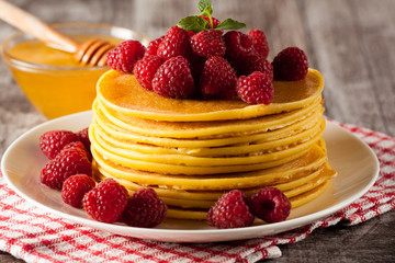 Fresh made delicious pancakes with berries, blackberries, raspberries, banana, honey and maple syrup. Healthy morning breakfast concept.