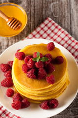 Fresh made delicious pancakes with berries, blackberries, raspberries, banana, honey and maple syrup. Healthy morning breakfast concept.