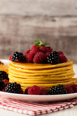 Fresh made delicious pancakes with berries, blackberries, raspberries, banana, honey and maple syrup. Healthy morning breakfast concept.
