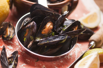 Boiled mussels in a cooking dish on wooden background close up