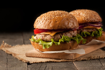 Close-up photo of home made hamburger with beer made of beef, onion, tomato, lettuce, cheese and spices. Fresh burger closeup on wooden rustic table with potato fries and chips.
