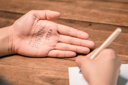 People cheating on test by writing answer on hand
