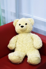 Bear doll with love heart sitting on red sofa