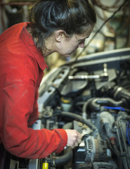 Fototapeta na wymiar Female mechanic inspecting car engine with wrench
