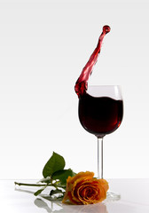 Weinglas mit Spritzer und Rose