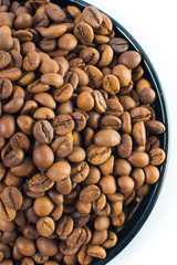 Coffee beans in a small plate on a white background. Isolated