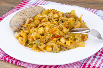 Homemade sausage with sauce of stewed cabbage on plate.