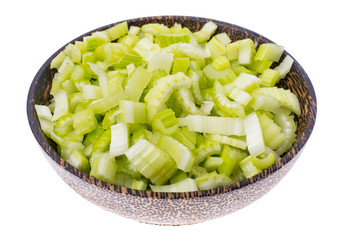 Pieces of celery in wooden bowl on white background, top view.