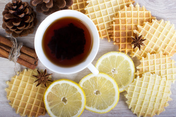 Cup of black tea with Christmas decor, lemon, pinecone, waffles, badian and cinnamon