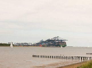 Stock Photo - blue sea structure cranes at cargo dock loading in distance felixstowe essex