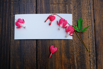 White greeting card on a wooden background with pink flowers.