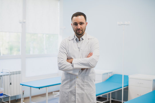 Portrait Of A Serious Confident Male Doctor Standing With Arms Crossed At Medical Office