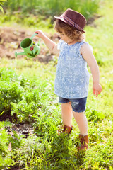 Toddler girl with the watering can in the garden