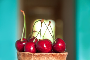 Cherry in a clay cup on the background of a window
