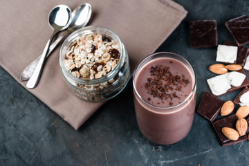 Glass of chocolate banana milkshake on dark  background, healthy breakfast