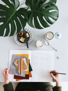 Overhead view of fashion designer sketching in book