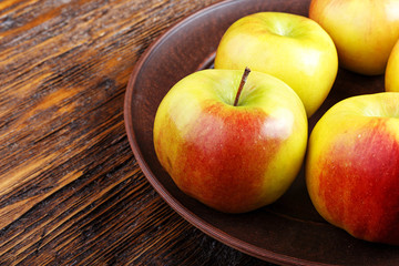 ripe in a dish apples on a wooden table, summer harvest, healthy