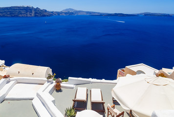 Santorini volcanic caldera as seen from view from the balcony with sun loungers in building Fira, capital of Santorini, Greece