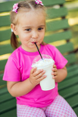 Fototapeta premium Little girl drinking milkshake through a straw