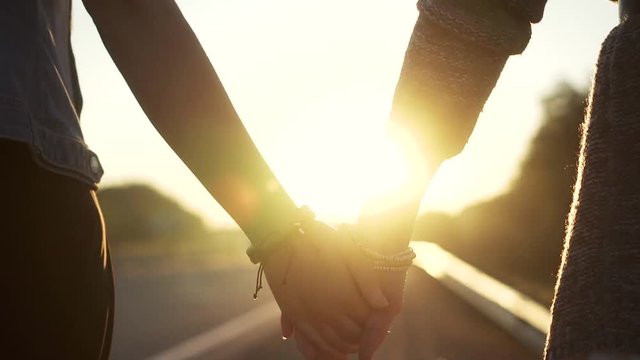 girlfriends hand at sunset, closeup. girls hold hands and walk down the road. slow motion