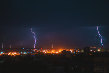Naklejka na ściany i meble Photo of beautiful powerful lightning over big city, zipper and thunderstorm, abstract background, dark blue sky with bright electrical flash, thunder and thunderbolt, bad weather concept