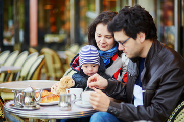 Happy family of three in Parisian outdoor cafe