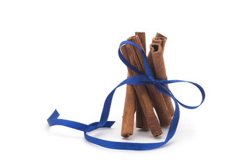Cinnamon sticks with blue ribbon on white background