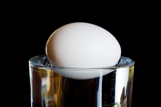 An Egg Floating In A Glass Of Water.