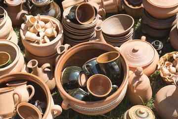 Group of traditional handmade pottery for sale at the market. Ukrainian handmade earthenware utensil. Souvenirs From Ukraine in ethnic style. Brown jugs and cups.