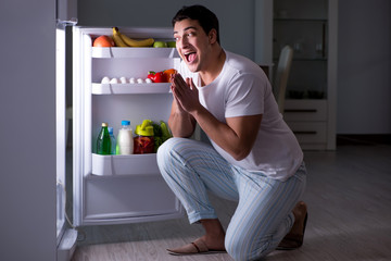 Man at the fridge eating at night