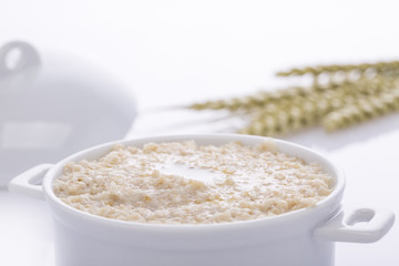 Oat porridge in a white saucepan. Oatmeal. Cap.