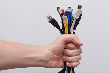 Hand holding out a bunch of computer cables with different connectors