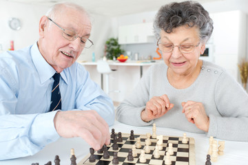 senior married couple playing chess at home