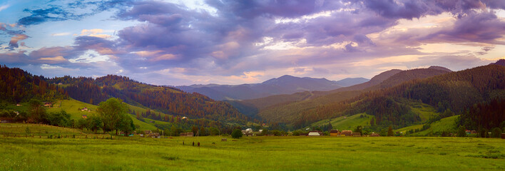 Carpathian mountains summer landscape with cloudy colorful sky and village at sunset, natural travel background